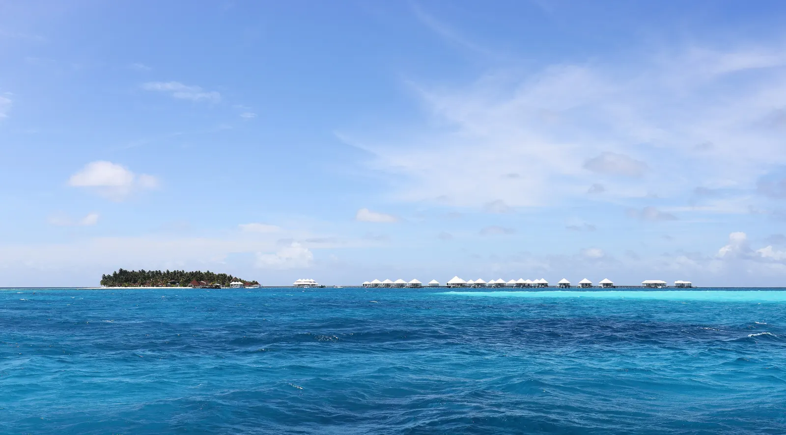 Wasservillen eines Resorts auf den Malediven am Horizont